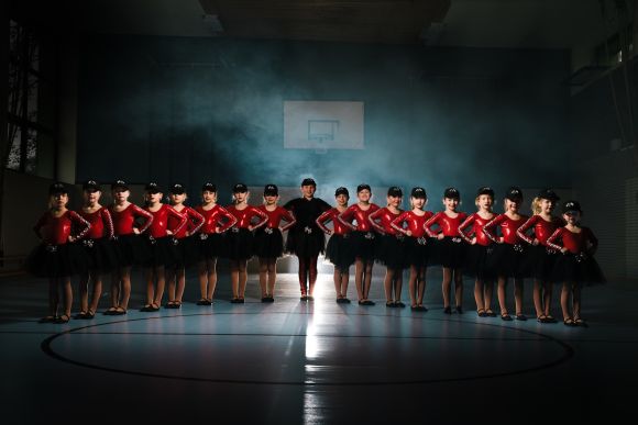 Junge Tänzerinnen der Großen Osterfelder Karnevalsgesellschaft 1906 e.V. sitzen in Uniform fröhlich auf einer Treppe.